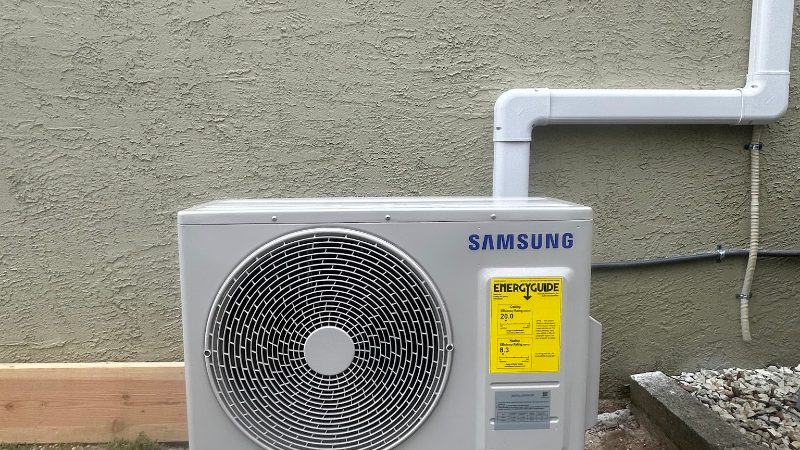 Outdoor heat pump unit installed on a pad beside a home by Comfort Pro