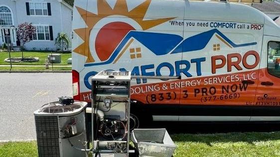 Comfort Pro branded van on a job with the replaced furnace and condenser on the lawn