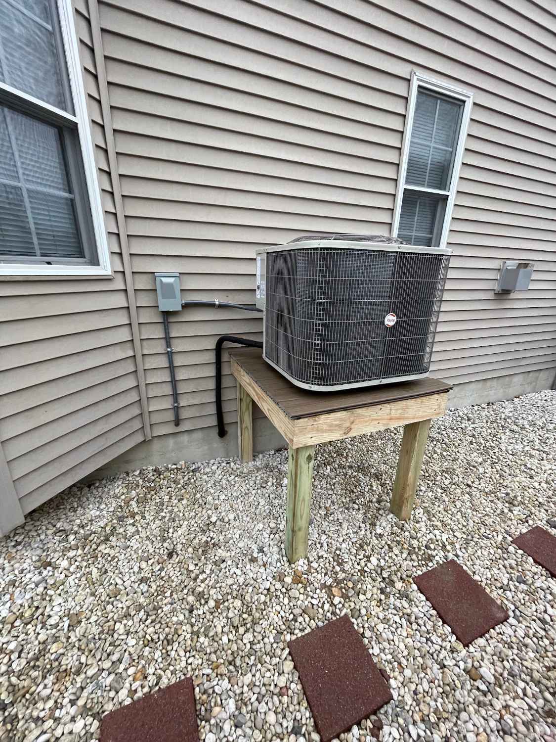 Air conditioning condenser raised on a stand beside a home in Cape May Court House NJ