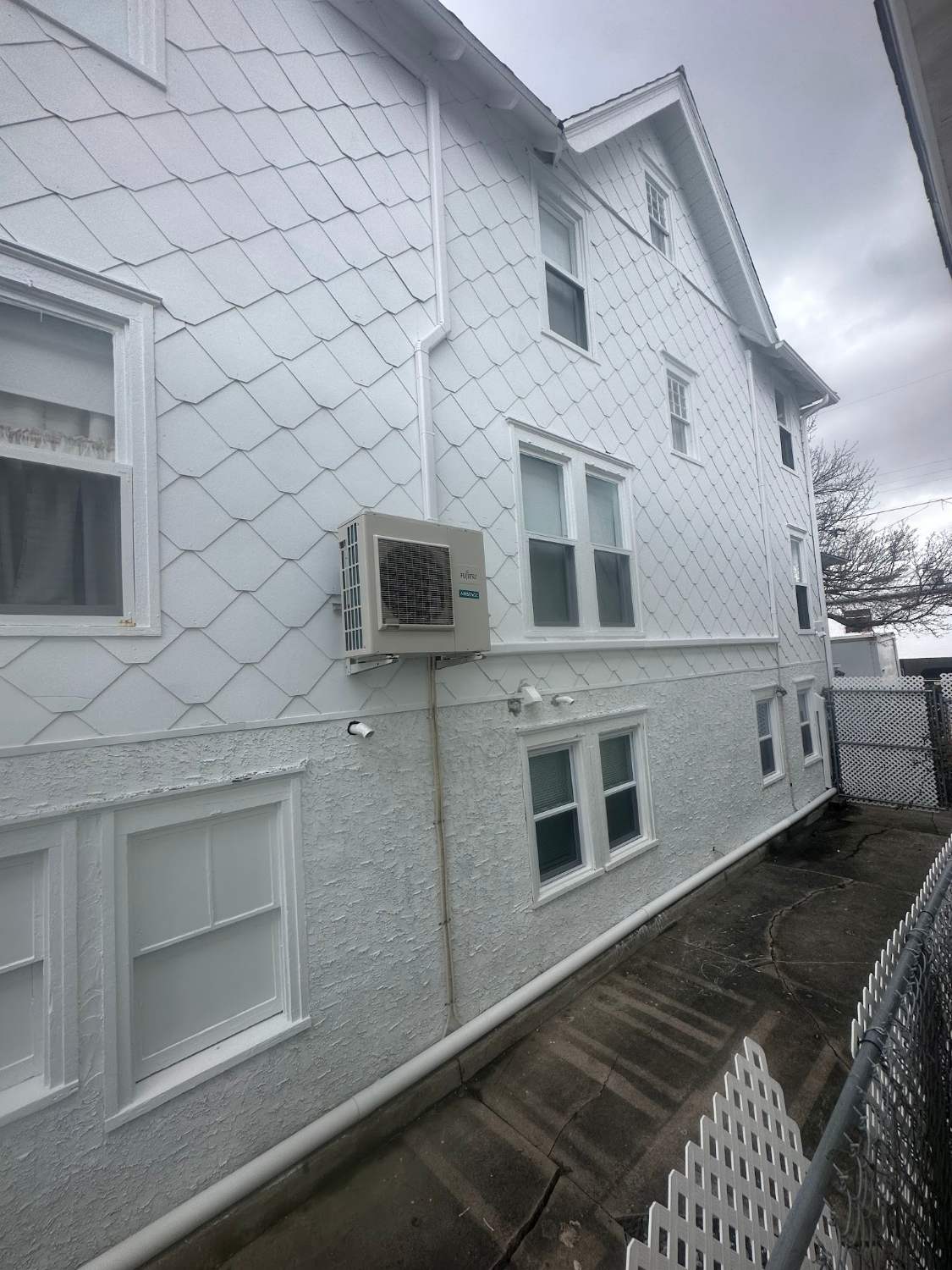 Ductless mini-split condenser mounted on a white shingled shore house in Wildwood NJ